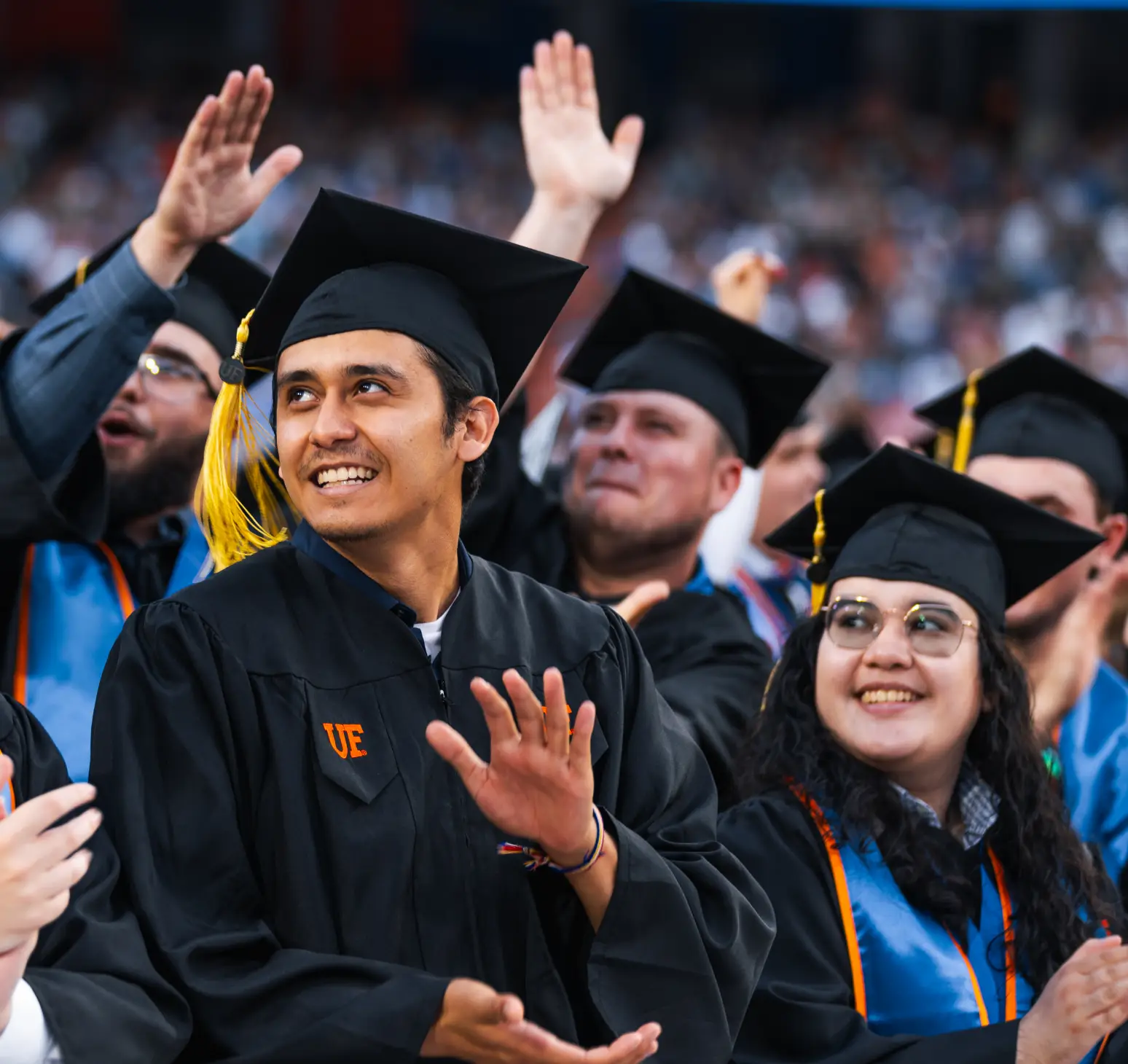 University of Florida graduates smile earnestly while doing the Gator chomp at their graduating ceremony