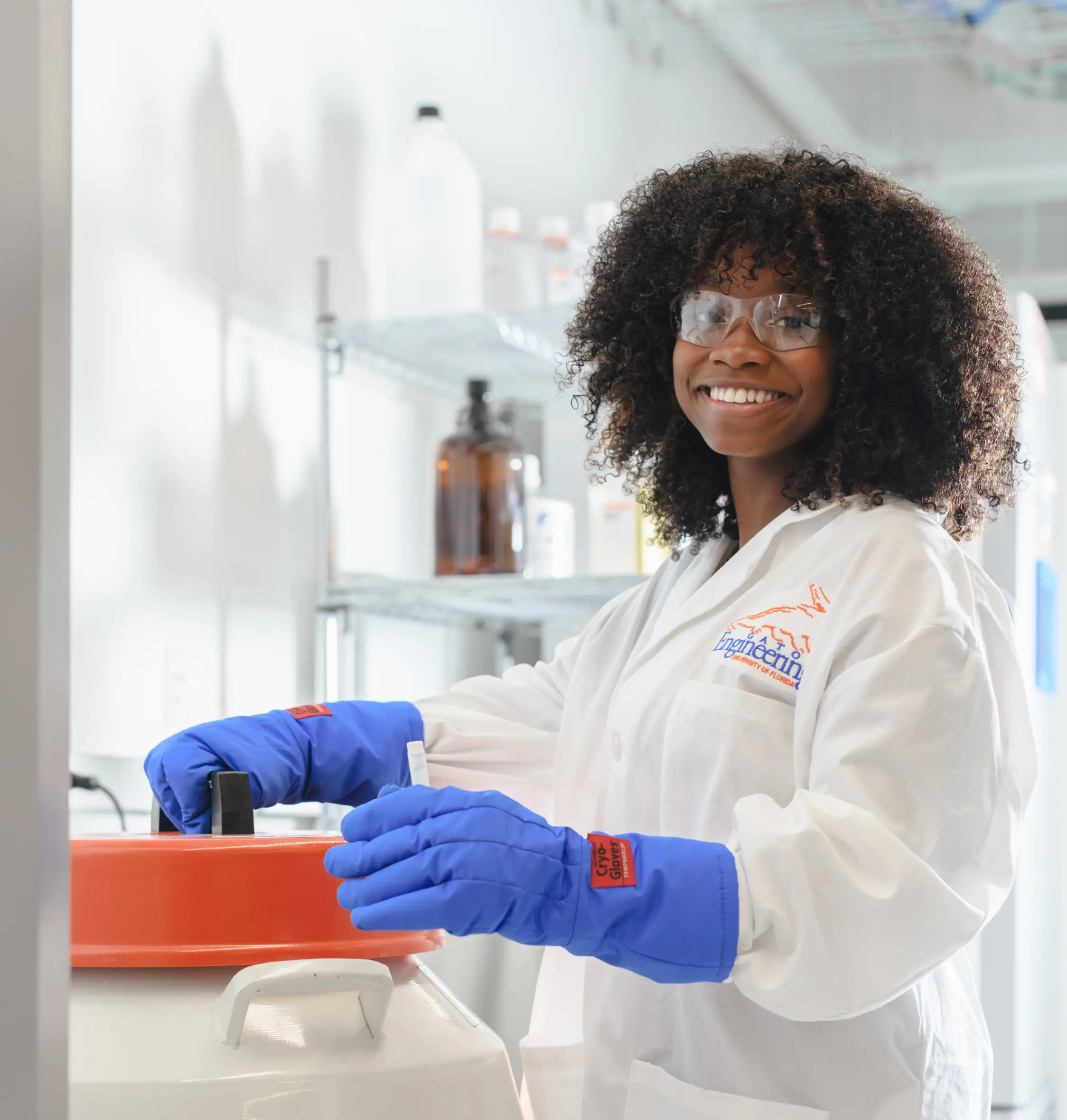 An engineering student smiles at the camera while handling equipment with Cryo-Gloves